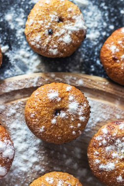 Siyah bir arka plan üzerinde şeker tozu ile ev yapımı cupcakes. Seçici odaklama, üst görünüm.