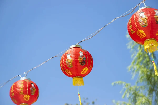 a collapsible paper lantern in bright colours, primarily red, used for decorative purposes, commonly painted with Chinese art.