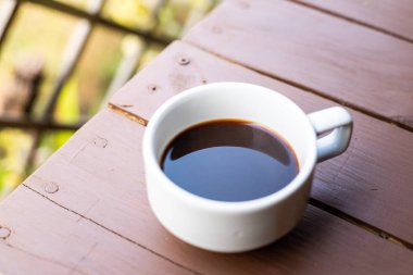 Ahşap masa üzerinde sıcak kahve ile beyaz kahve bardağı closeup.