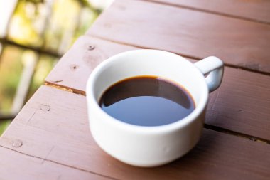 Ahşap masa üzerinde sıcak kahve ile beyaz kahve bardağı closeup.