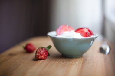 Mavi seramik kase çilek ahşap masa üzerinde taze çilek ile yoğurt., seçici odak ile organik yoğurt