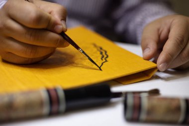 Kaligrafi desen yakın atölyesinde ciltli bir kitap sarı kapak ellerinde boyama kitabı cilt el