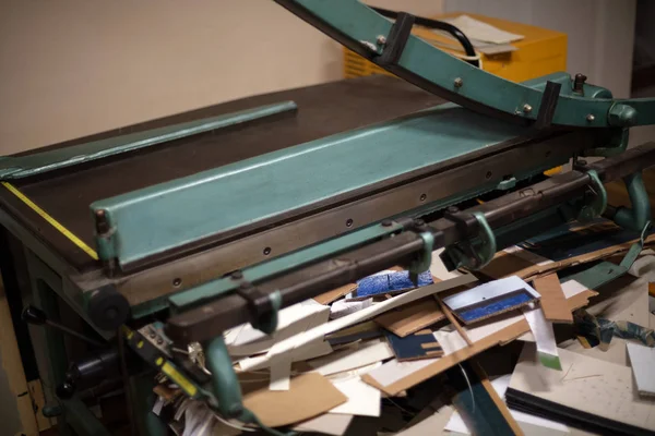 Büyük giyotin kesme kağıt ile düşük bir açıda kaldırdı bıçağı için yapılmayan dağınık atölyecilik masa üzerinde görünümü kapatın