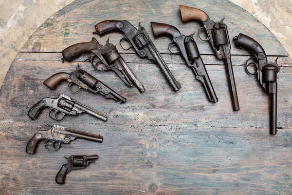 High resolution image of historical guns and pistols on a vintage wood background in an exhibit in a museum or collectors showcase
