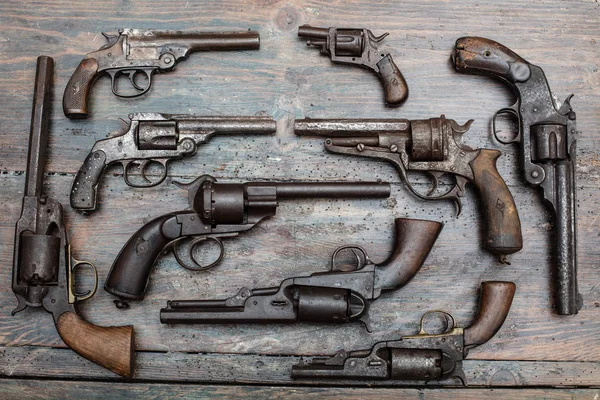 High resolution image of historical guns and pistols on a vintage wood background in an exhibit in a museum or collectors showcase