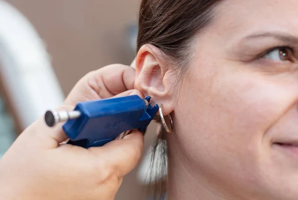 Kadın güzellik merkezi tıbbi işçi tarafından işlem özel delici silahla piercing kulak sahip kırpılmış görünümü Kapat