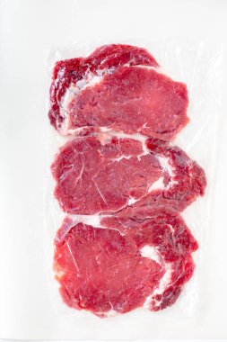 Beyaz arka plan üzerinde üstten görünüm izole taze çiğ Dana biftek şeffaf Vakumlu