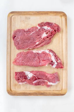 Beyaz arka plan üzerinde üstten görünüm izole ahşap kesme tahtası üzerinde taze çiğ Dana biftek