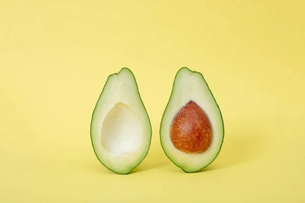 Two slices of avocado isolated on yellow background — Stock Photo, Image