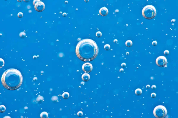 青い水の中で上向きに押し上がる酸素の泡. — ストック写真