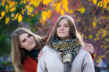 Portre iki güzel mutlu kız parkta bir yürüyüş için güneşli bir sonbahar gününde.