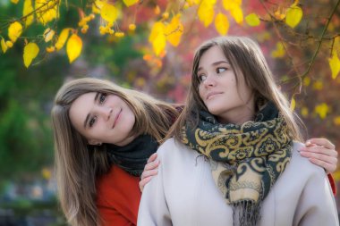 Portre iki güzel mutlu kız parkta bir yürüyüş için güneşli bir sonbahar gününde.