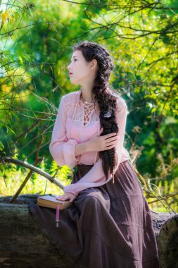 Boho tarzı giysiler içindeki genç kız ormana inzivaya kitap okuma.