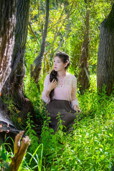 年轻美丽体贴的女孩坐在树下的森林 — 图库照片
