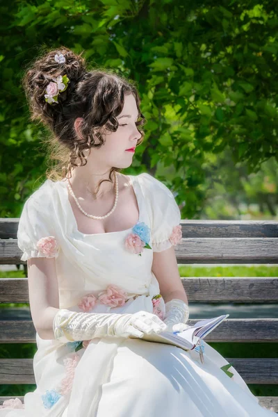 Junges Mädchen Schicken Langen Weißen Kleid Liest Auf Einer Parkbank — Stockfoto
