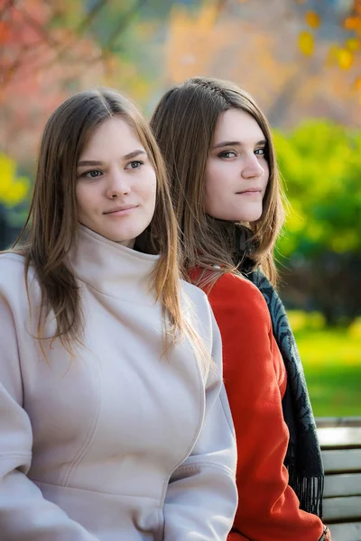 Портрет Двух Красивых Молодых Женщин Соперниц Сидящих Бок Бок Скамейке — стоковое фото