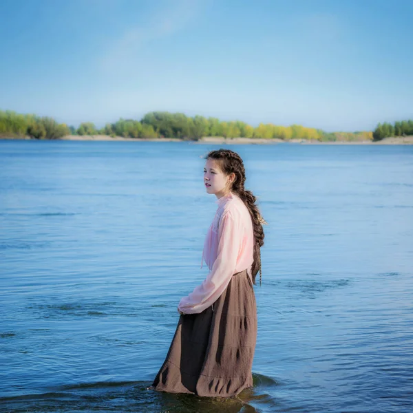 夏の晴れた日の美しい悲しい少女が川に立っています — ストック写真