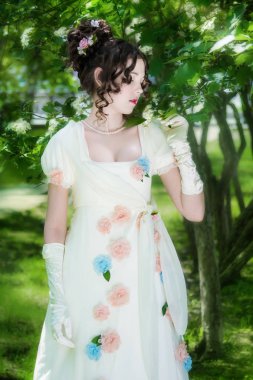 Bir bahar bahçe çiçek açan bush yakınındaki bir zarif uzun beyaz gelin elbiseli genç kadın.