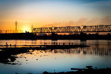 Cityscape günbatımı zemin karşı bir köprü ile ırmak.