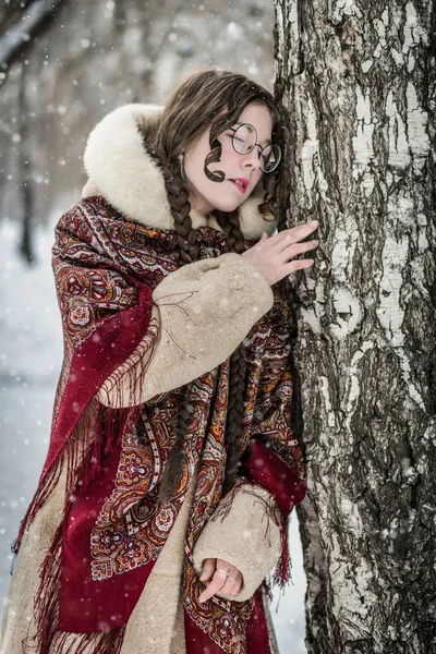 一个闭着眼睛的女人在冬天的一天在桦树附近穿着皮大衣的肖像 — 图库照片