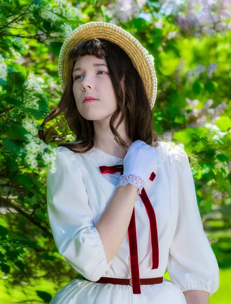 Girl in a white dress and straw hat near flowers hawthorn — Stock Photo, Image