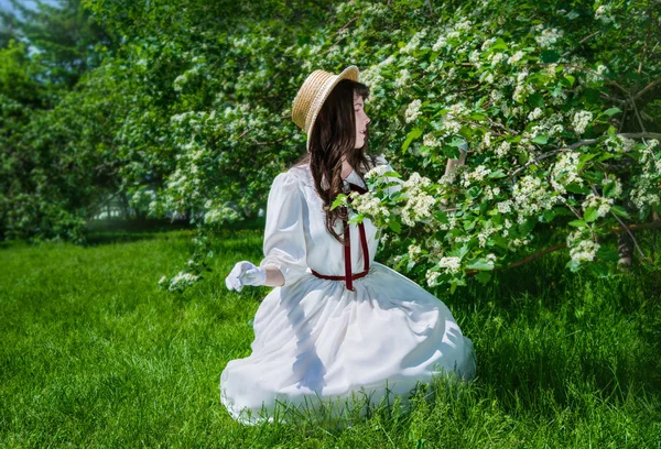 白いドレスの少女が花を調べ. — ストック写真
