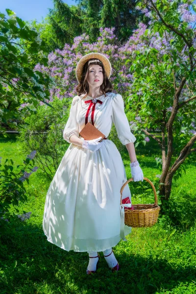 Chica un libro y una cesta en sus manos en el jardín — Foto de Stock