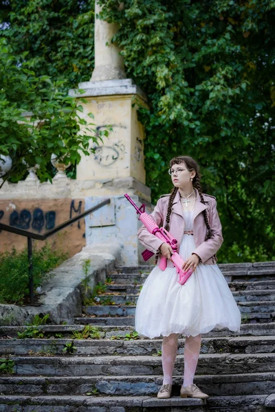 Ragazza con un fucile rosa salire sui gradini delle scale . — Foto Stock