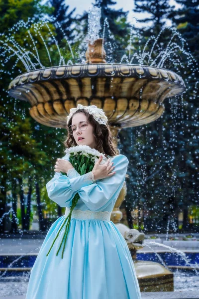 噴水のそばに立つヴィンテージドレスの花束を持つ肖像の女の子 — ストック写真