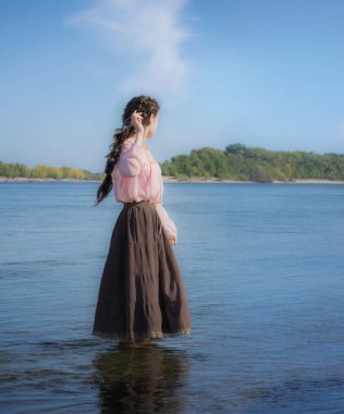 Üzgün kadın nehirde duruyor.