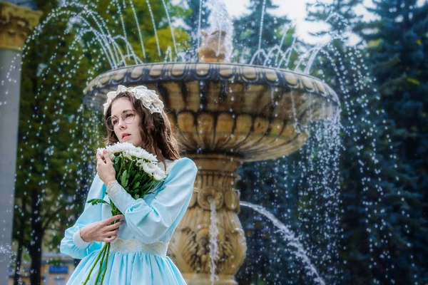 噴水のそばに立つヴィンテージドレスの花束を持つ肖像の女の子 — ストック写真