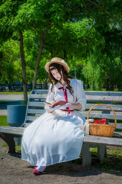 Chica joven está leyendo un libro sentado en un banco . —  Fotos de Stock