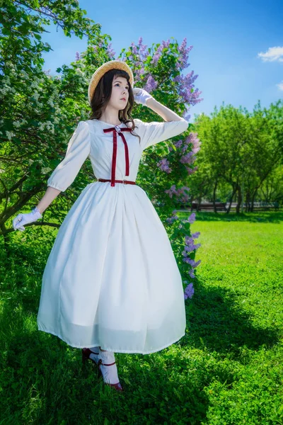 Chica en un vestido blanco y sombrero de paja camina — Foto de Stock