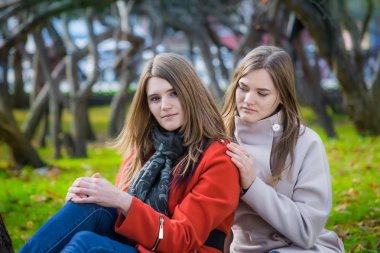 Parkta çimenlerde oturan iki güzel kız arkadaş.