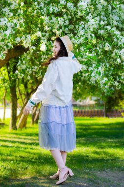 Genç ve güzel bir kadın, güneşli bir günde bir parkta dans ederek seviniyor.