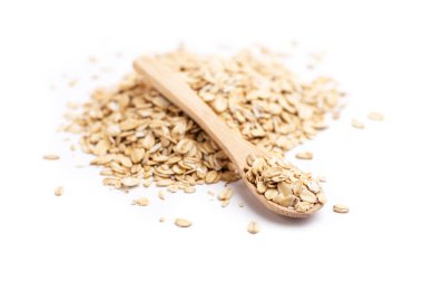 Beyaz arka planda izole edilmiş bir yığın yulaf ezmesinin üzerinde tam ahşap bir kaşığın yan görüntüsü