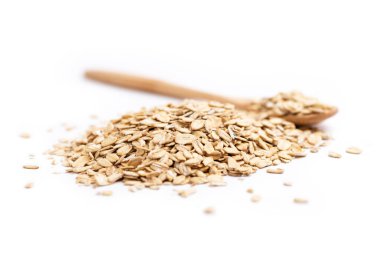 Sağda dolu bir tahta kaşık ve beyaz arka planda izole edilmiş bir yığın yulaf ezmesi.