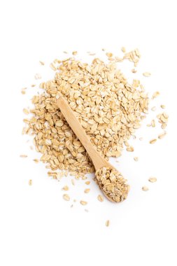 Beyaz bir arka planda izole edilmiş bir yığın yulaf ezmesinin üzerinde tam bir tahta kaşığın üst görüntüsü.