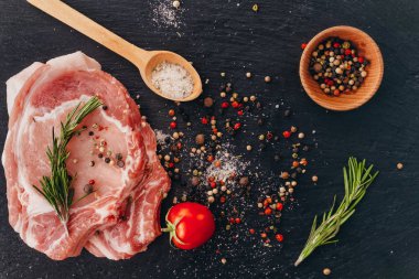 Bir masada baharat ile pişmemiş çiğ domuz pirzolası. Düz yatıyordu.