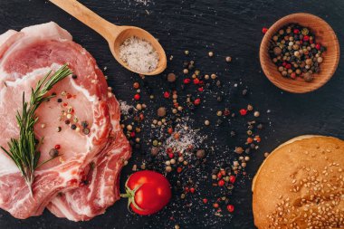 Bir masada baharat ve hamburger topuz ile pişmemiş çiğ domuz pirzolası