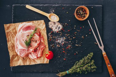 Bir masada baharat ve barbekü çatal ile pişmemiş çiğ domuz pirzolası . 