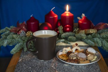 Erster Advent. Ein Zeichen fuer die Weihnachtszeit ist der erste Advent. Ein Symbol dafuer ist die erste brennende Kerze auf dem Adventskranz. Plaetzchen zum Kaffee die richtige Weihnachtsstimung 'u getirdi