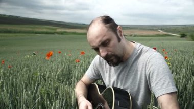 Erkekler dışarıda siyah akustik gitar alanında oynuyor.