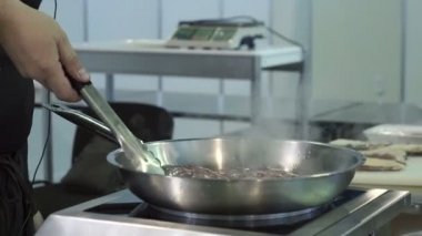 Aşçı pan et kızartma. Adam yanan tavada et kızartma. Bir tava üzerinde ateş. Yakın çekim.