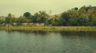 Kırsal manzara. Yeşil çayır nehrin karşı. Nehir kıyısında küçük evler ile köy.