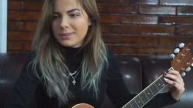 Genç kız evde akustik gitar çalmak