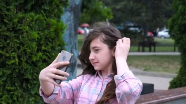 Çekici kız selfie ile onların hücre telefon alıyor. Esmerler gülümsüyor ve çok mutlu görünüyorsunuz. Açık havada.