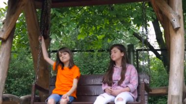 Mutlu çocuklar yaz Park'ta bir salıncak üzerinde binmek. Sevimli Genç kız açık havada oyun alanı salıncaklar.