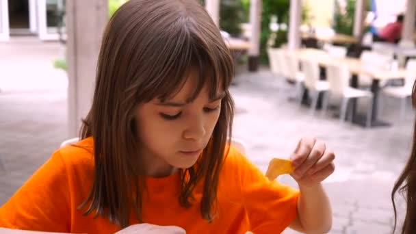 Mała dziewczynka jedzenie w kawiarni, fast food. — Wideo stockowe