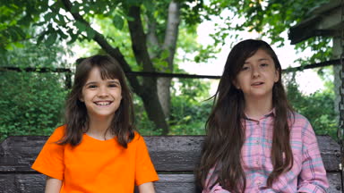 Mutlu çocuklar yaz Park'ta bir salıncak üzerinde binmek. Sevimli Genç kız açık havada oyun alanı salıncaklar.